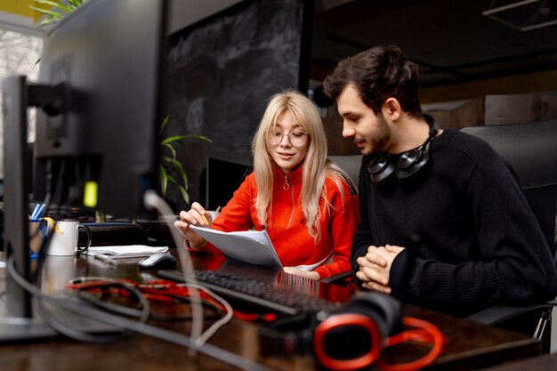 Twee collega's bespreken problemen in een modern kantoor. man en vrouw collega's zitten aan tafel met computer. Bedrijfsplan.