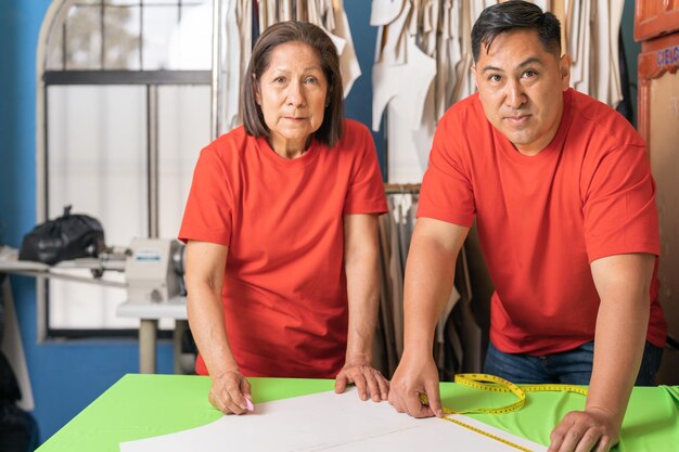 Twee collega's met rood shirt kijken naar de camera in een textielatelier