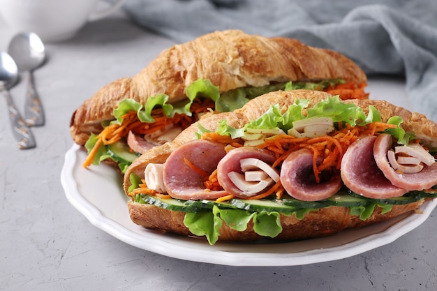 Twee croissants met sla, wortelen, komkommers, worst en kaas