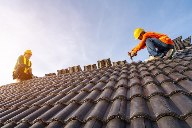 Twee dakdekker die aan de dakstructuur van het gebouw op de bouwplaats werkt