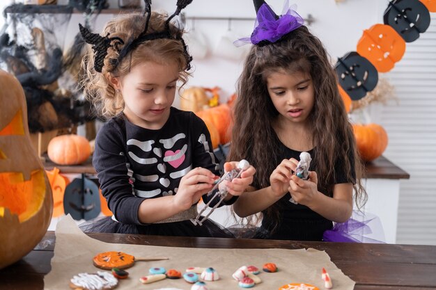 Twee diverse kinderen meisje in kostuum van heks, plezier thuis in de keuken, halloween vieren.