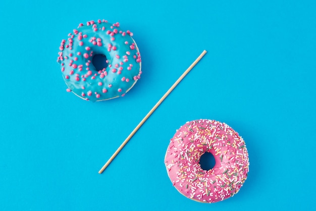 Twee donuts gescheiden met rietje op blauw.