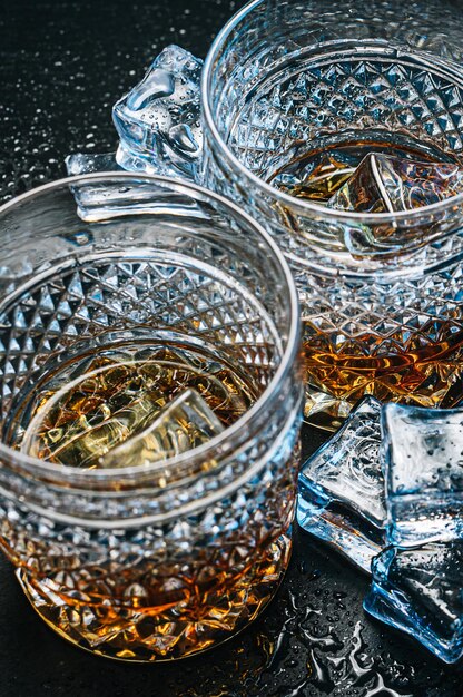 Twee dure glazen whisky met ijs op een zwart stenen dienblad