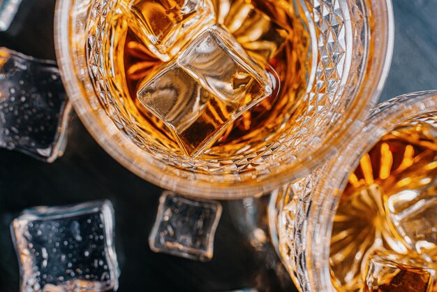 Twee dure glazen whisky met ijs op een zwart stenen dienblad