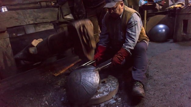 twee echte brutale traditionele smidsarbeiders die samenwerken met een roodgloeiend ijzer met behulp van mechanische hamer op workshop Portret van een beroep
