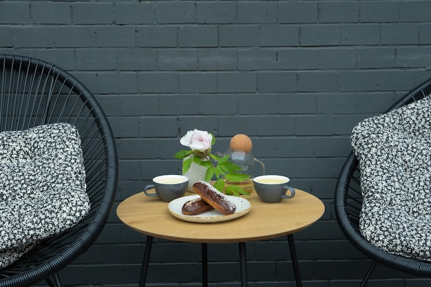 Twee eclairs met twee kopjes thee op een tafel in een café Zoet voedsel stilleven