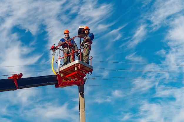 Twee elektrici uit de wieg van een luchtplatform of kraan repareren een straatverlichting