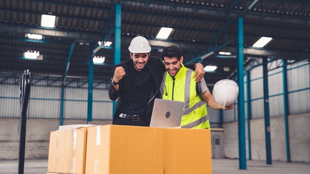 Twee fabrieksarbeiders vieren succes samen in de fabriek of het magazijn