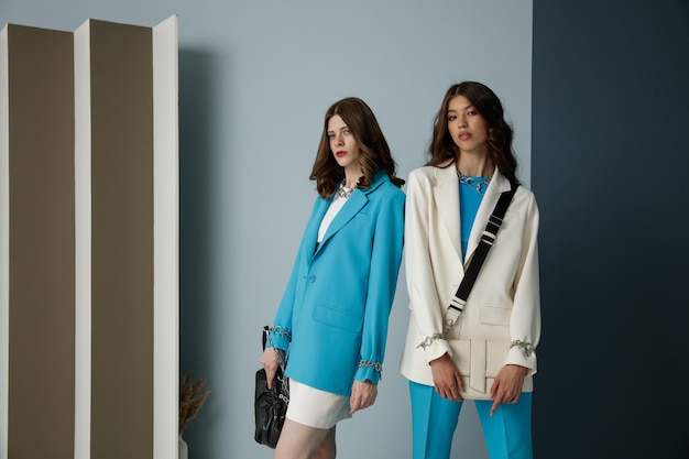 Twee fashion modellen in aqua blauw witte looks Jas blazer rok top broek broek handtas