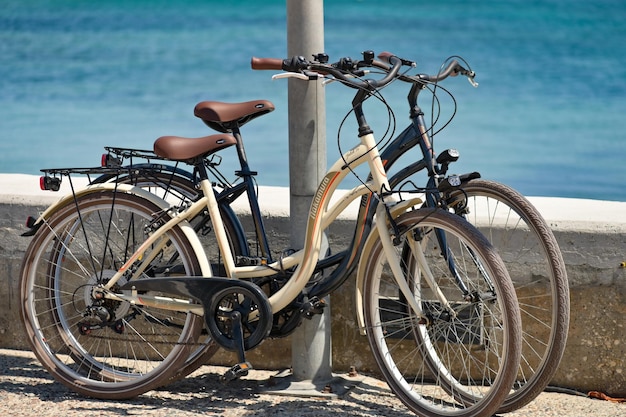 Twee fietsen staan naast de zee op het strand geparkeerd