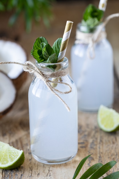 Twee flessen kokoswater op een houten lijst.