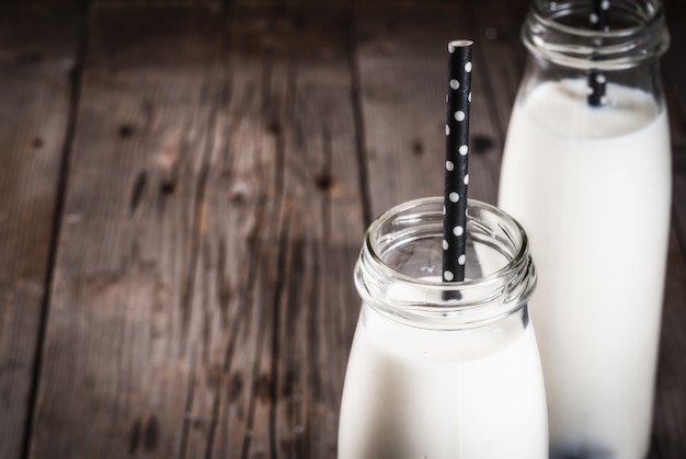 Twee flessen organische rustieke melk op een oude houten lijst. kopieer ruimte dichtbij bekijken