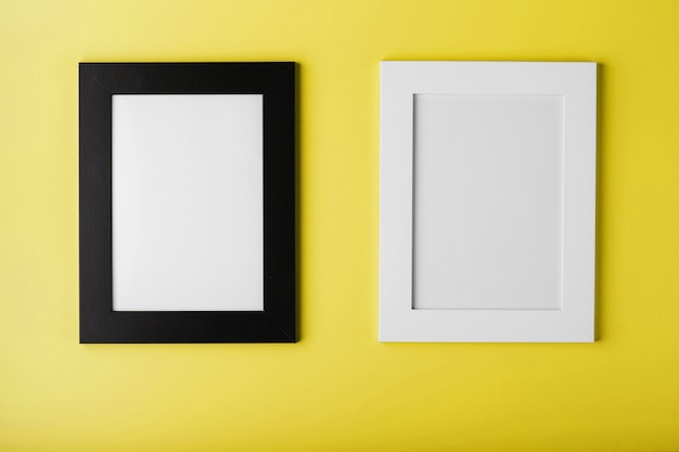 Twee frames Witte en zwarte fotolijst op geel oppervlak met vrije ruimte. Minimalistisch concept