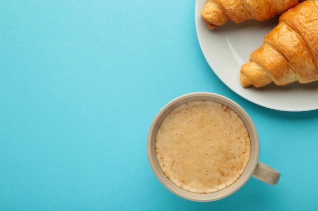 Twee Franse croissants op plaat en kopje koffie op blauwe achtergrond