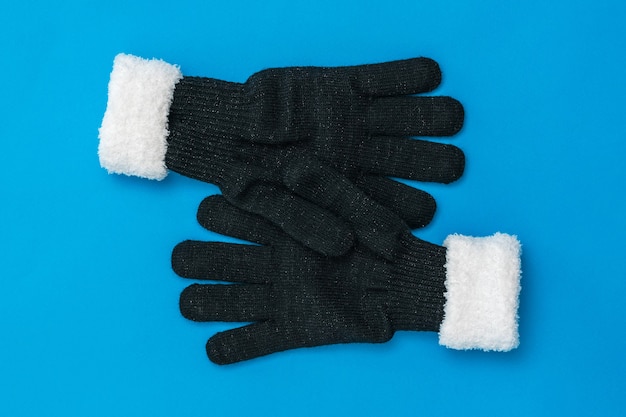 Twee gebreide handschoenen omhelzen elkaar op een blauwe achtergrond. Het concept van hoop en ontmoeting. Mode accessoires voor dames.