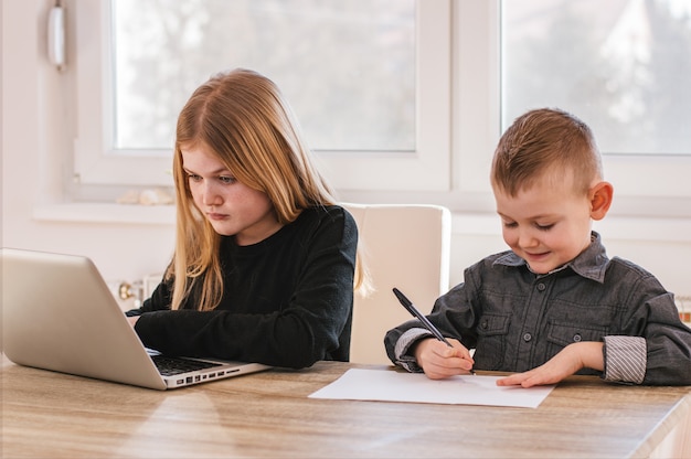 Twee geconcentreerde kleine kinderen met laptop schrijven