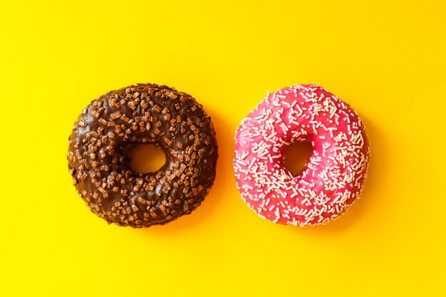 Twee geglazuurde donuts geïsoleerd op geel