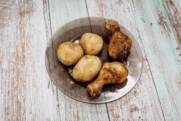 Twee gegrilde kippenpoten en aardappelen op het bord