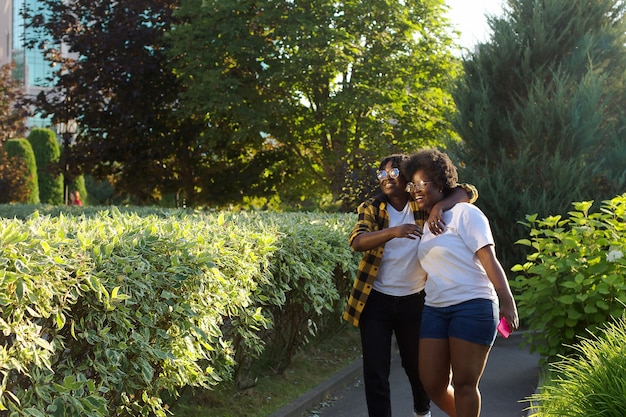 Twee gelukkige Afro-Amerikaanse vrouwen lopen in de zomer over straat.