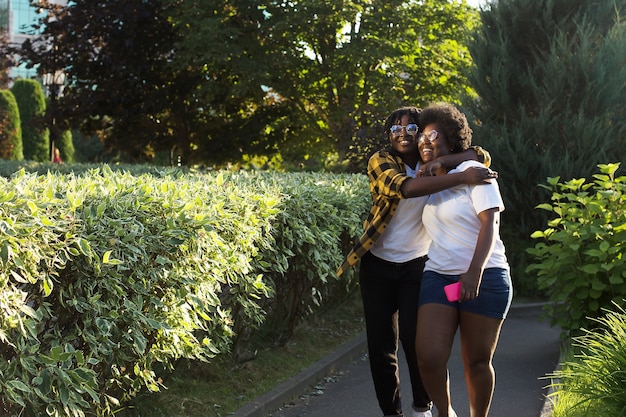 Twee gelukkige Afro-Amerikaanse vrouwen lopen in de zomer over straat.