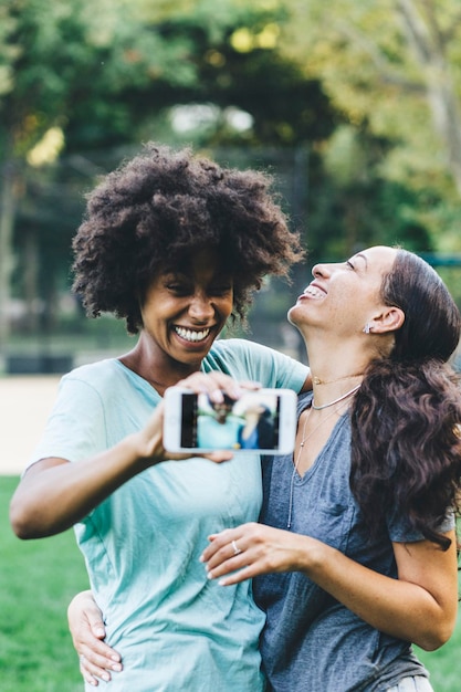 Twee gelukkige beste vrienden nemen selfie met smartphone in een park