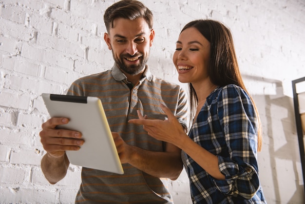 Twee gelukkige collega's werken met een tablet in kantoor