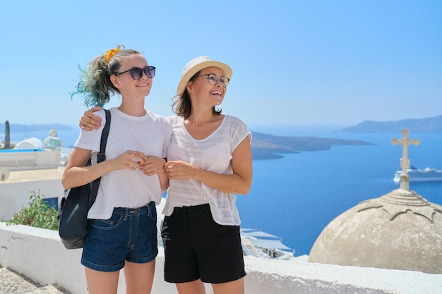 Twee gelukkige glimlachende vrouwen, moeder en tienerdochter die samen reizen, luxe reizen naar het beroemde Griekse eiland Santorini