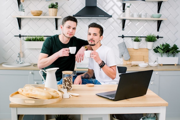 Twee gelukkige homomannen in homewear die ochtend in de keuken doorbrengen. Gelukkige homoseksuelen die thuis ontbijt in de ochtend hebben