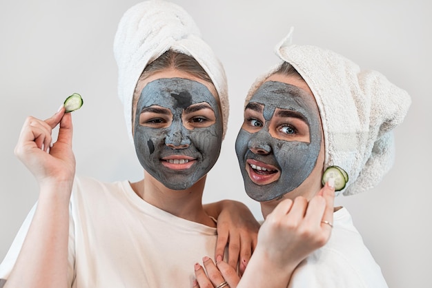 Twee gelukkige jonge vrouwen brengen een kleimasker aan op het gezicht en genieten van vrije tijd Huidverzorging anti-verouderingsbehandeling