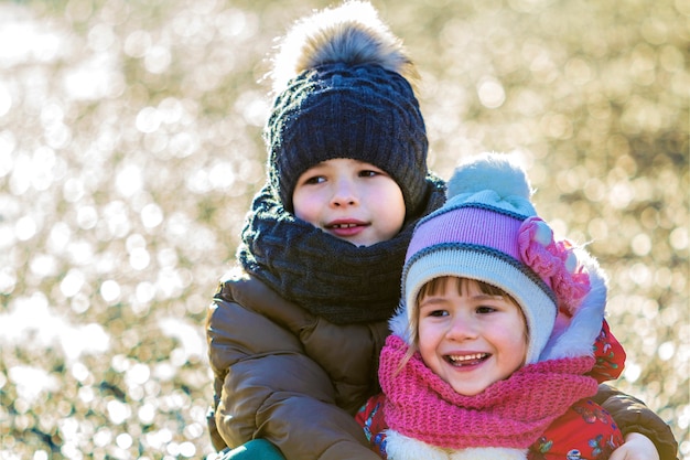 Twee gelukkige kinderen jongen en meisje buiten in zonnige winterdag