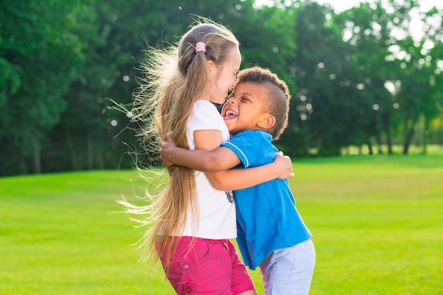 Twee gelukkige kinderen staan op de open plek om elkaar te omhelzen en te glimlachen