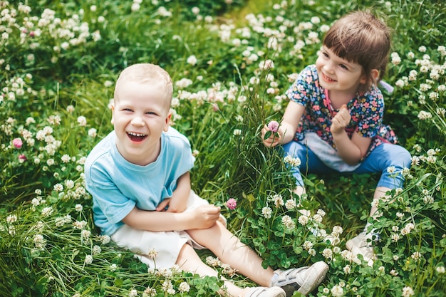 Twee gelukkige kindervrienden, een jongen en een meisje, zittend op een klaverveld, samen plezier maken