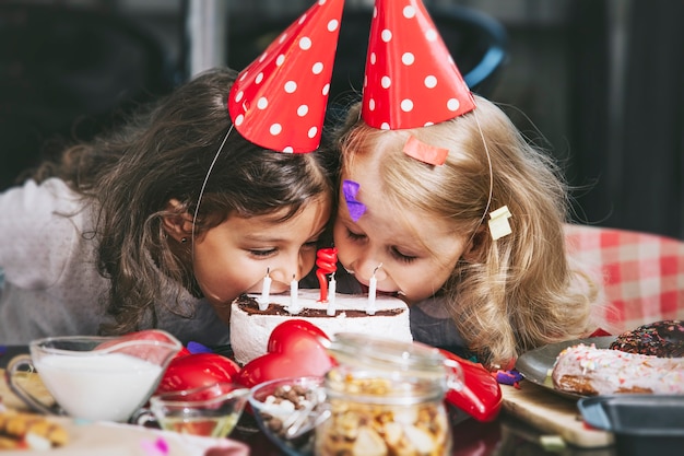 Twee gelukkige kleine meisjes kind een verjaardag vieren met taart aan tafel is mooi en mooi