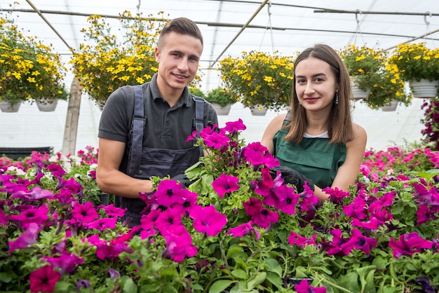 Twee gelukkige tuinmannen in schorten werken met bloemenplanten in de natuurkastuin. Lente seizoen