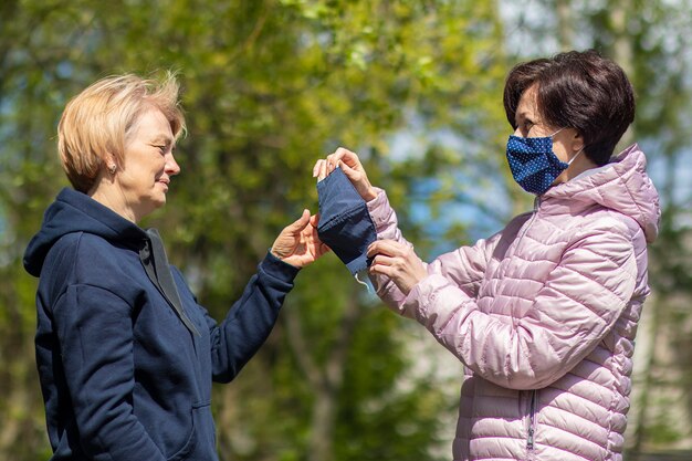 Twee gelukkige volwassen vrouwen dragen van beschermende maskers