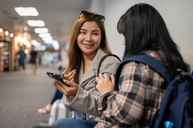 Twee gelukkige vriendinnen genieten van een gesprek terwijl ze op de luchthaven wachten op hun instaptijd