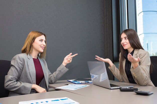 Twee gelukkige zakenvrouwen die op kantoor werken.