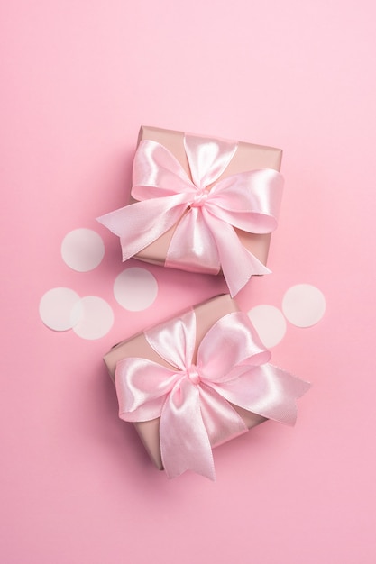 Twee geschenken of geschenkdozen versierd met confetti op roze pastel.