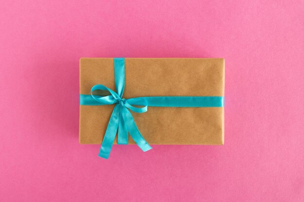 Twee geschenkkistjes verpakt in ambachtelijk papier en blauw lint op de roze achtergrond