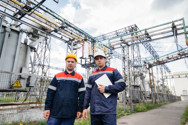 Twee gespecialiseerde onderstationingenieurs inspecteren moderne hoogspanningsapparatuur