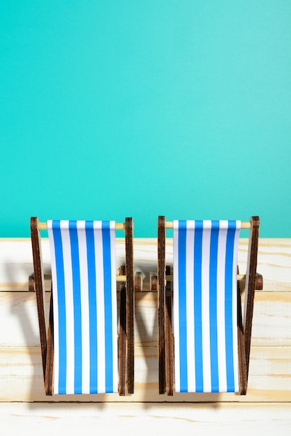 Twee gestreepte strandstoelen op houten oppervlak en blauwe achtergrond
