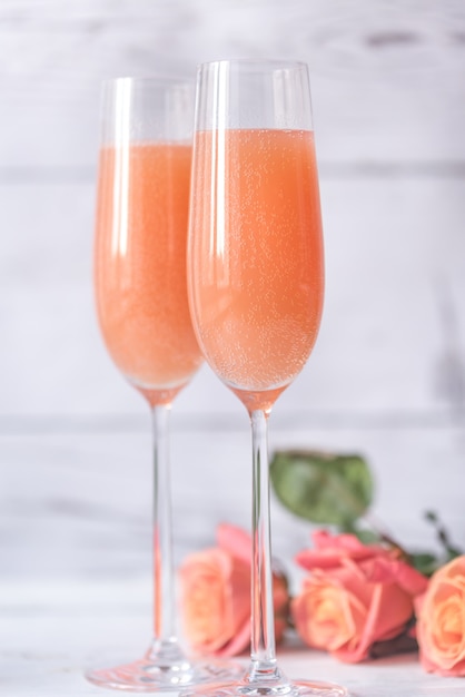 Twee glazen bellini cocktail met boeket rozen