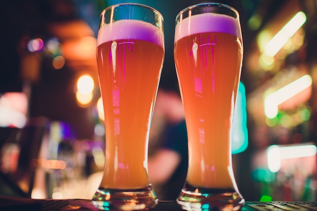 Twee glazen bier op een bartafel. biertap op achtergrond.