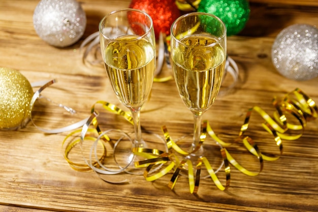 Twee glazen champagne en feestelijke kerstversieringen op houten tafel Kerst- en nieuwjaarsviering