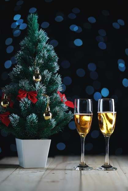 Twee Glazen Champagne en Kleine Kerstboom Donkere Gloedlichten Achtergrond.