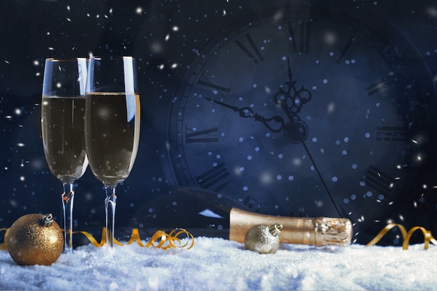 Twee glazen champagne met gouden lint, ster en bal met sneeuw