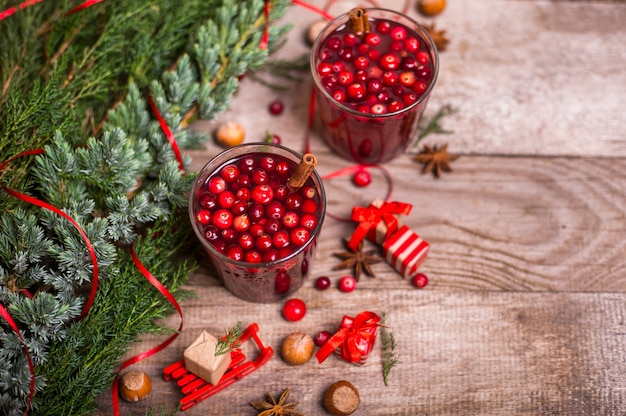 Twee glazen cranberry drinken, veenbessen, kaneelstokjes, anijs sterren op een houten tafel. kerst winter drankjes.