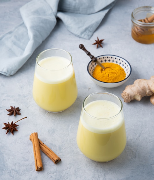 Twee glazen gouden melk met kurkuma op blauwe achtergrond