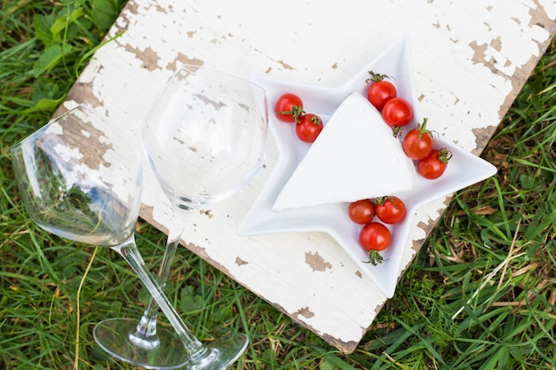 Twee glazen kaas en tomaten op een bord op gras