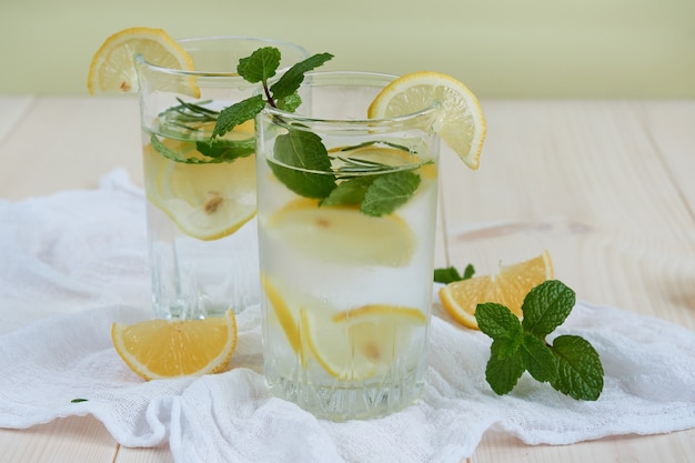 Twee glazen koele limonade met citroen en munt op een wit servet